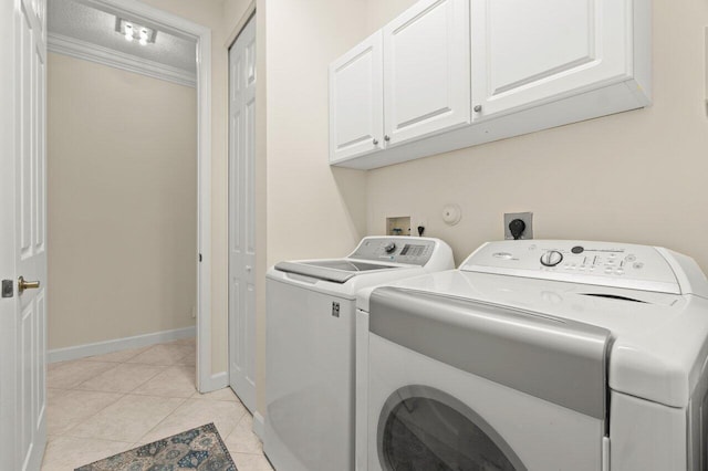 washroom with cabinet space, light tile patterned floors, baseboards, ornamental molding, and washer and dryer