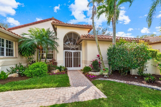 entrance to property featuring a tiled roof and stucco siding