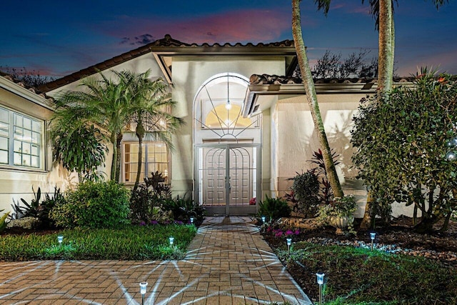 exterior entry at dusk featuring stucco siding