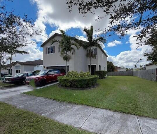 view of side of property featuring concrete driveway, an attached garage, fence, a yard, and stucco siding