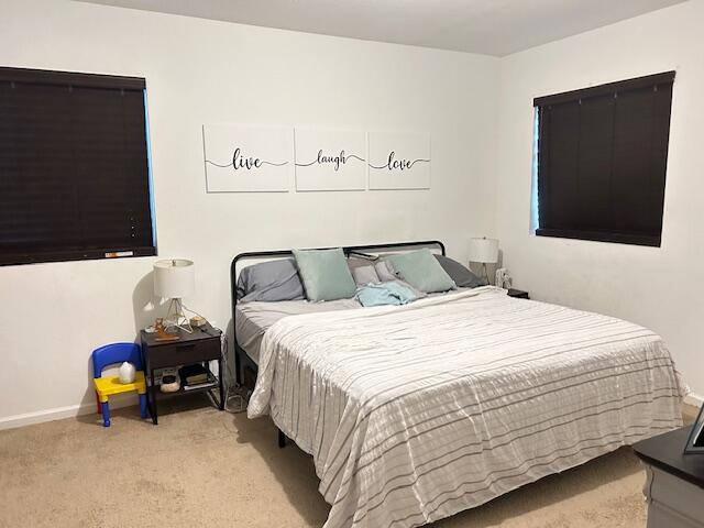bedroom featuring light carpet and baseboards