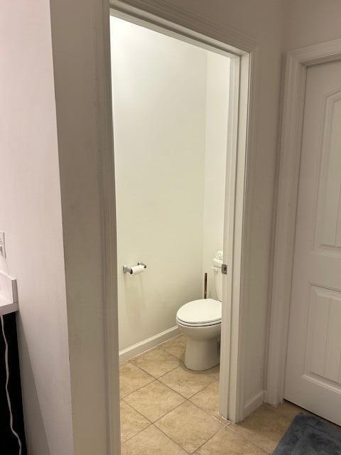 bathroom featuring tile patterned flooring, baseboards, and toilet