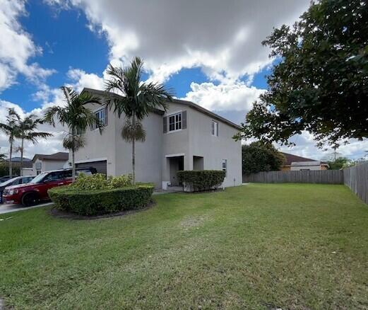 view of home's exterior featuring a garage, a lawn, fence, and stucco siding