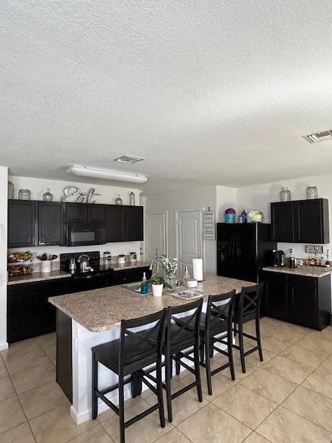 kitchen with dark cabinets, a sink, and black appliances