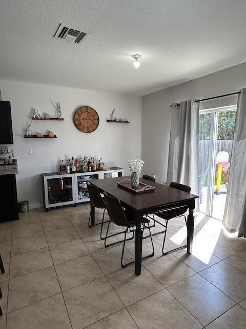 dining space with visible vents, a textured ceiling, and light tile patterned flooring