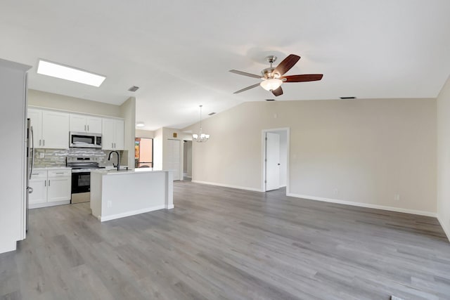 kitchen featuring stainless steel appliances, white cabinetry, open floor plan, hanging light fixtures, and light countertops