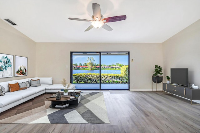 living area featuring a ceiling fan, wood finished floors, visible vents, and baseboards