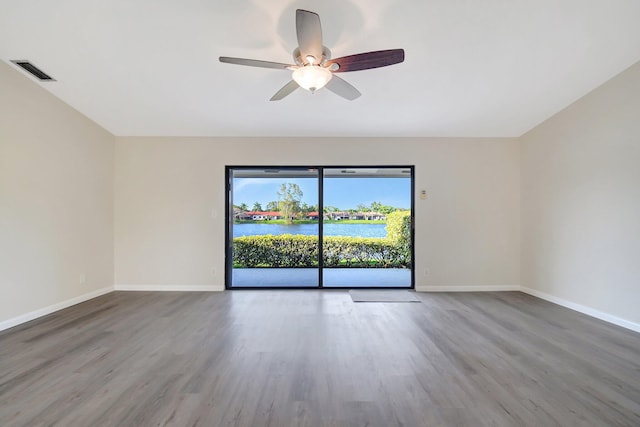 empty room featuring a water view, baseboards, and wood finished floors