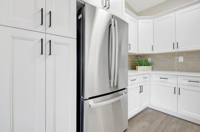 kitchen with light countertops, decorative backsplash, freestanding refrigerator, white cabinetry, and light wood-type flooring