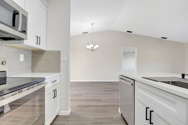 kitchen with decorative light fixtures, stainless steel appliances, light countertops, white cabinets, and light wood-type flooring