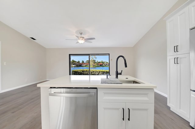 kitchen featuring an island with sink, light countertops, stainless steel dishwasher, white cabinetry, and a sink