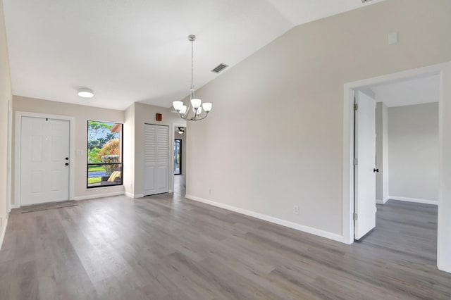 unfurnished dining area featuring lofted ceiling, wood finished floors, visible vents, and an inviting chandelier