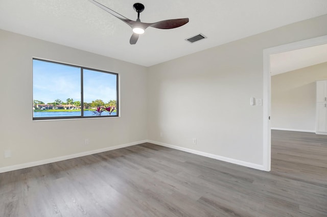 spare room with visible vents, ceiling fan, baseboards, and wood finished floors