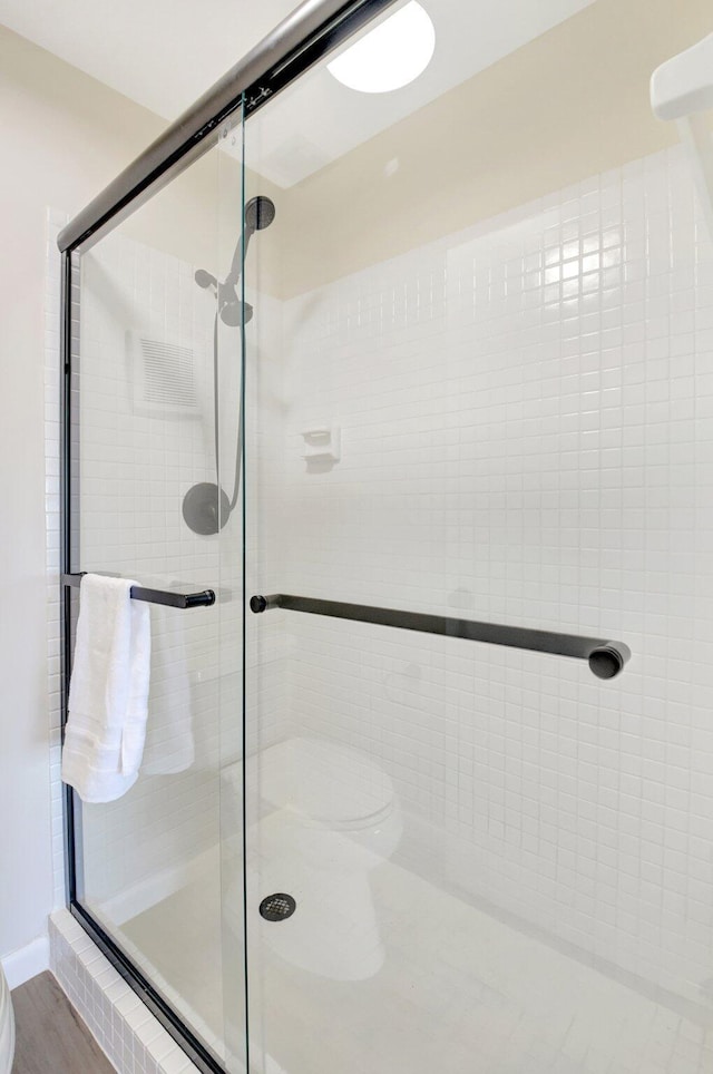 bathroom with a stall shower and wood finished floors