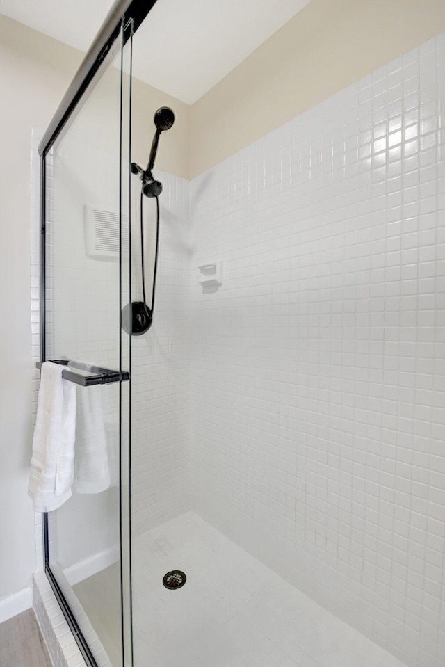 full bath featuring wood finished floors, a shower stall, and baseboards