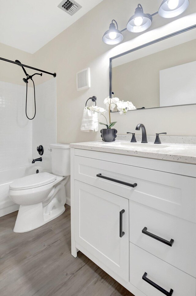 full bathroom with visible vents, toilet, tub / shower combination, vanity, and wood finished floors