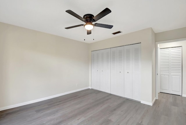 unfurnished bedroom featuring a ceiling fan, light wood-style floors, visible vents, baseboards, and a closet