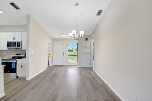 entryway featuring a chandelier, light wood-type flooring, visible vents, and baseboards