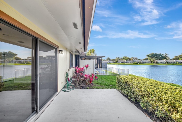 view of patio with a water view and fence