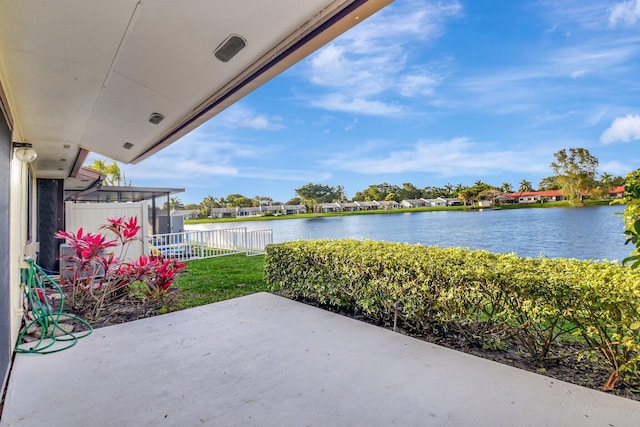 view of patio featuring a water view and fence