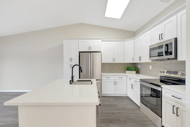 kitchen featuring stainless steel appliances, white cabinetry, and a center island with sink