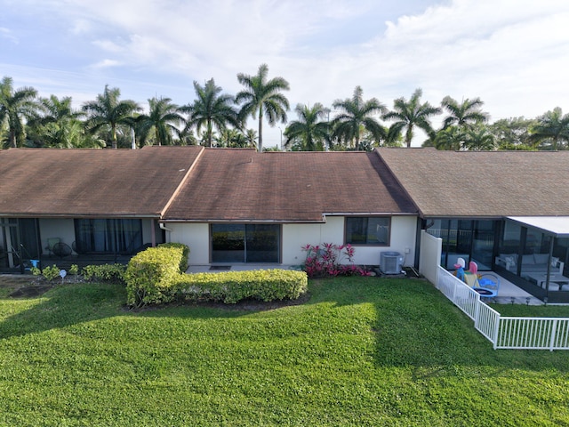 view of front of property featuring a shingled roof, central AC, fence, and a front lawn