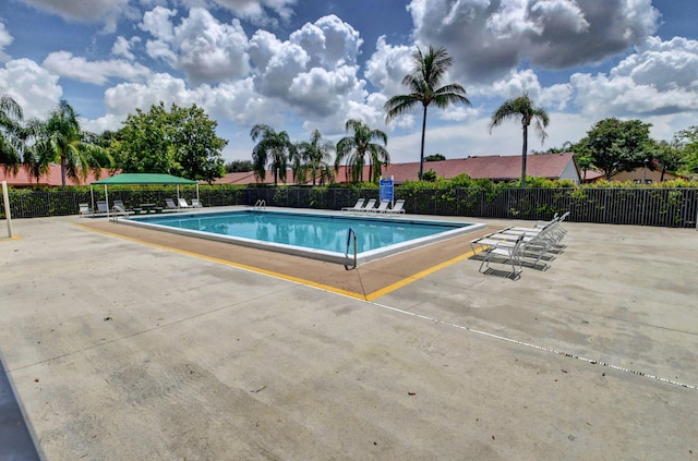 community pool with a patio area and fence