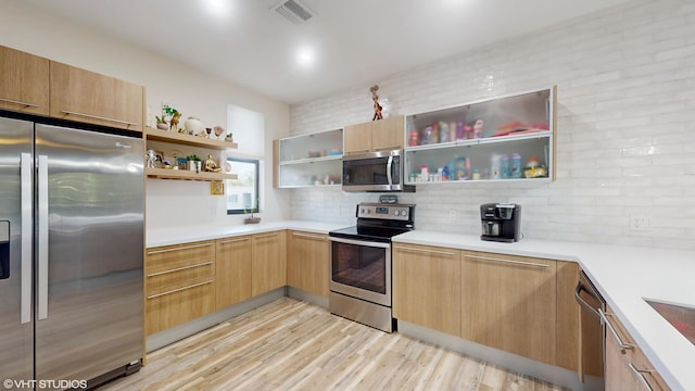 kitchen featuring light countertops, appliances with stainless steel finishes, decorative backsplash, open shelves, and light wood finished floors