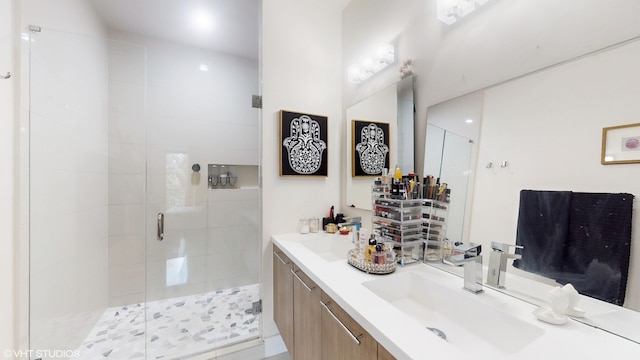 full bath featuring a sink, a shower stall, and double vanity