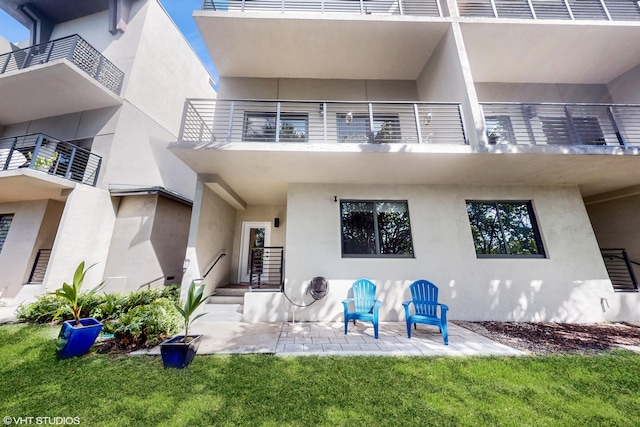 property entrance featuring a patio area, a balcony, and stucco siding