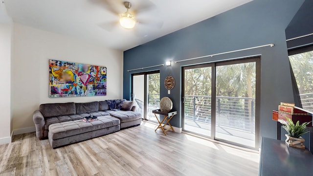 living area with a ceiling fan, wood finished floors, a wealth of natural light, and baseboards