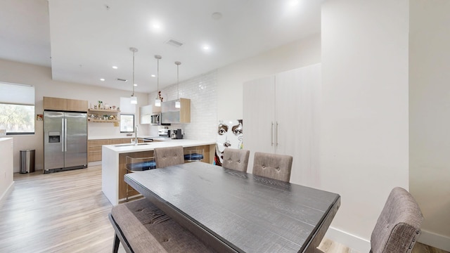 dining room featuring a wealth of natural light, baseboards, visible vents, and light wood finished floors