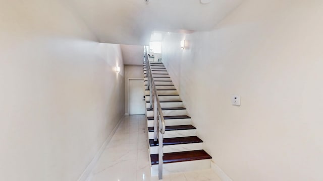 stairway featuring marble finish floor and baseboards