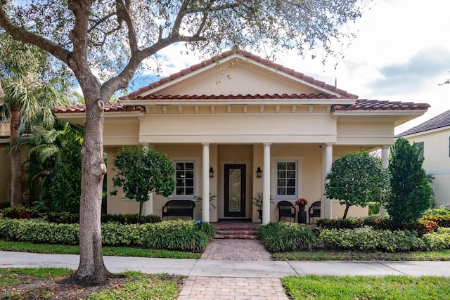 mediterranean / spanish home featuring a porch and stucco siding