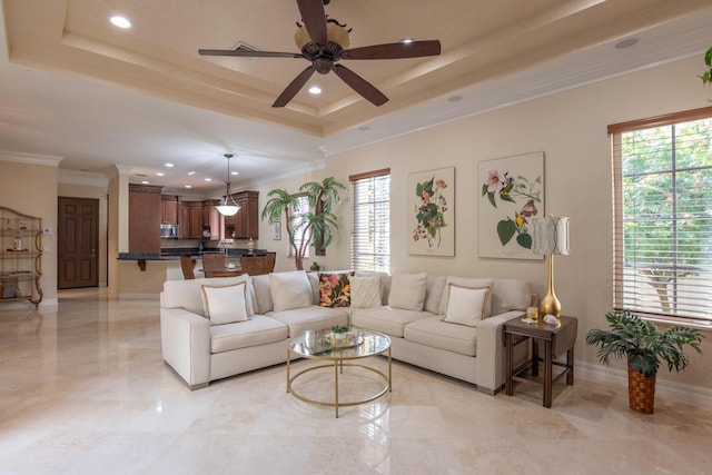 living room featuring ornamental molding, a raised ceiling, and a wealth of natural light