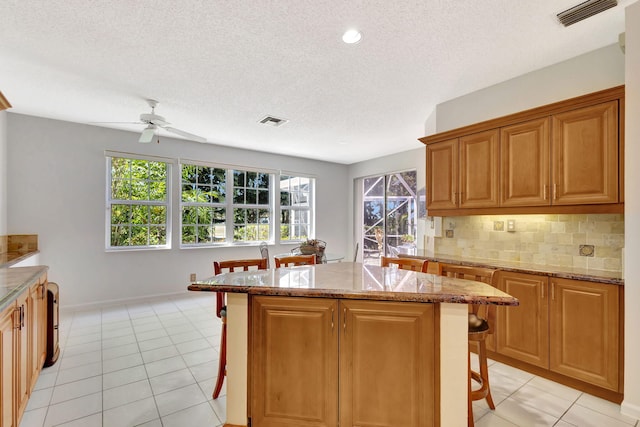 kitchen featuring decorative backsplash, visible vents, a breakfast bar area, and light tile patterned floors