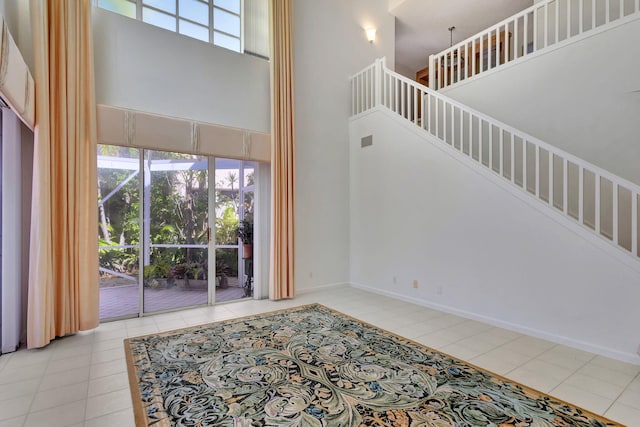 living room featuring a wealth of natural light, tile patterned floors, a high ceiling, and stairs