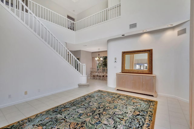 tiled foyer entrance with a high ceiling, visible vents, stairway, and baseboards