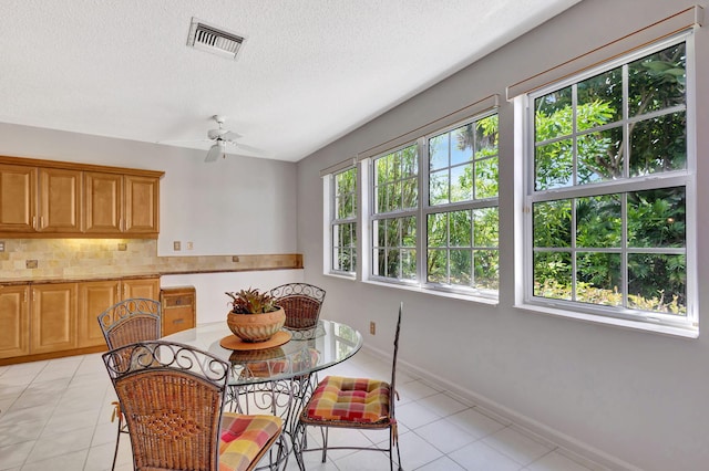 dining area featuring light tile patterned floors, visible vents, baseboards, ceiling fan, and a textured ceiling