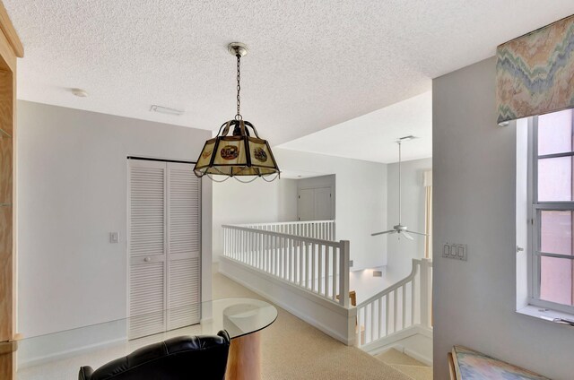 interior space with a textured ceiling and an upstairs landing