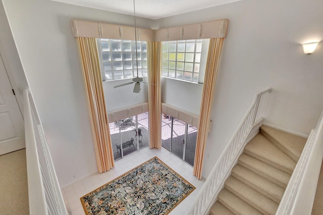 stairs with ceiling fan and baseboards