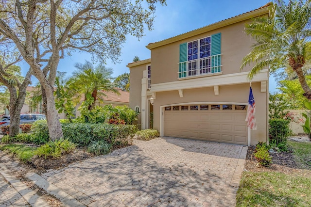 view of front of home featuring an attached garage, decorative driveway, and stucco siding