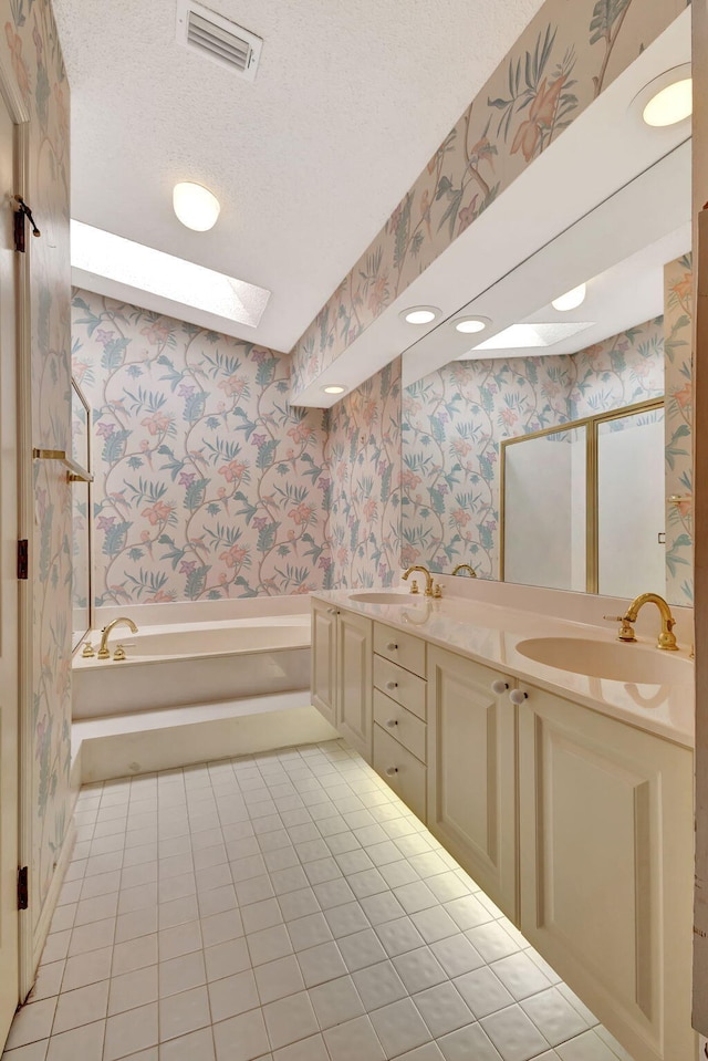 bathroom featuring a textured ceiling, a skylight, a sink, visible vents, and wallpapered walls