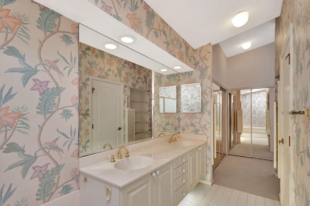 full bathroom with double vanity, wallpapered walls, and a sink