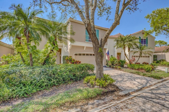 mediterranean / spanish-style house featuring a garage, a tiled roof, decorative driveway, and stucco siding