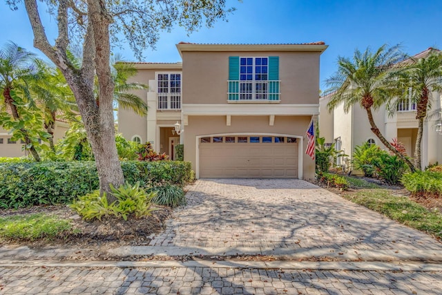 view of front facade with a tiled roof, decorative driveway, an attached garage, and stucco siding