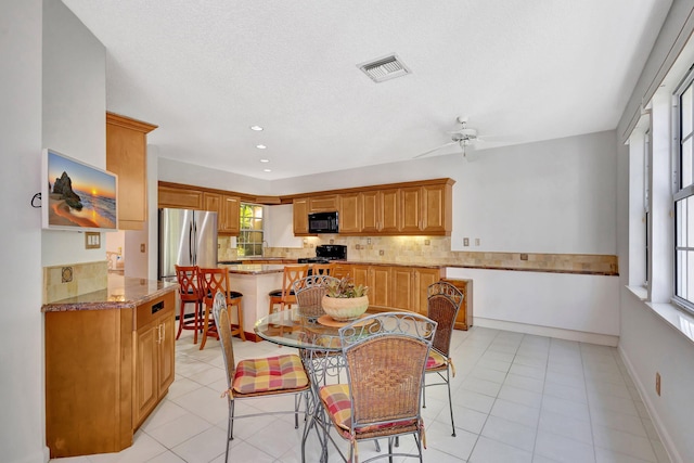 dining room with a ceiling fan, light tile patterned flooring, visible vents, and baseboards