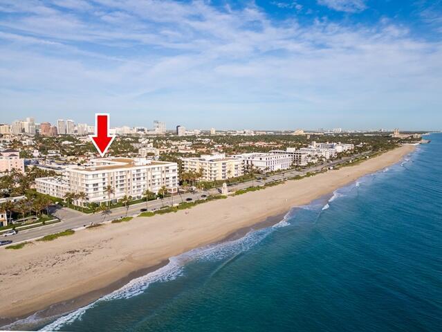 drone / aerial view with a water view, a city view, and a view of the beach