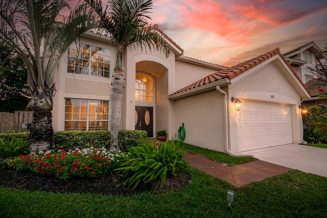 mediterranean / spanish-style home featuring driveway, a tiled roof, an attached garage, and stucco siding