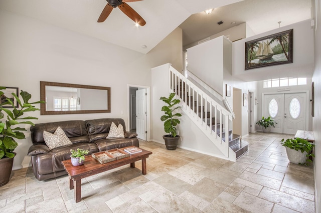 living area with high vaulted ceiling, stone tile flooring, stairway, and baseboards